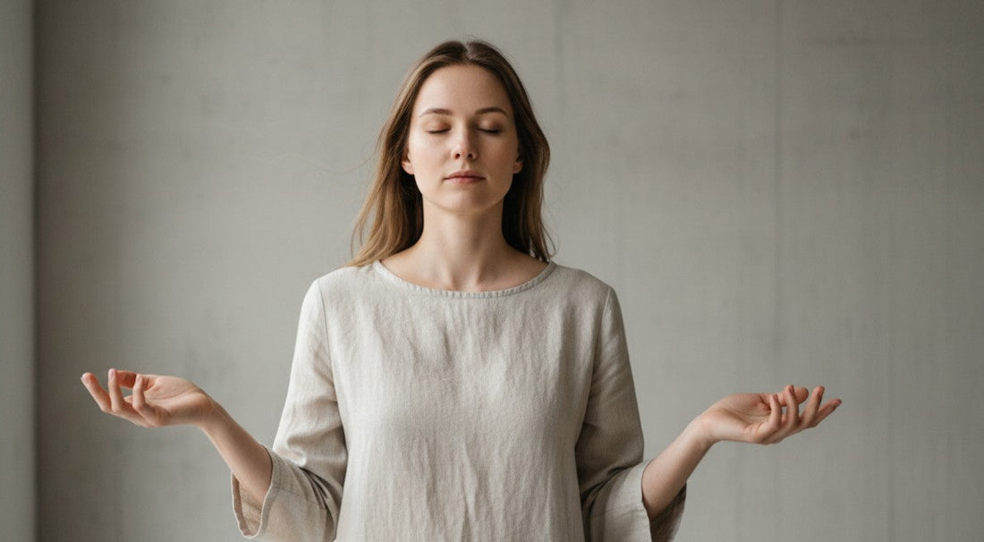 A person standing with eyes closed and hands relaxed, practicing mindfulness and sensory awareness in a calm minimalist space.