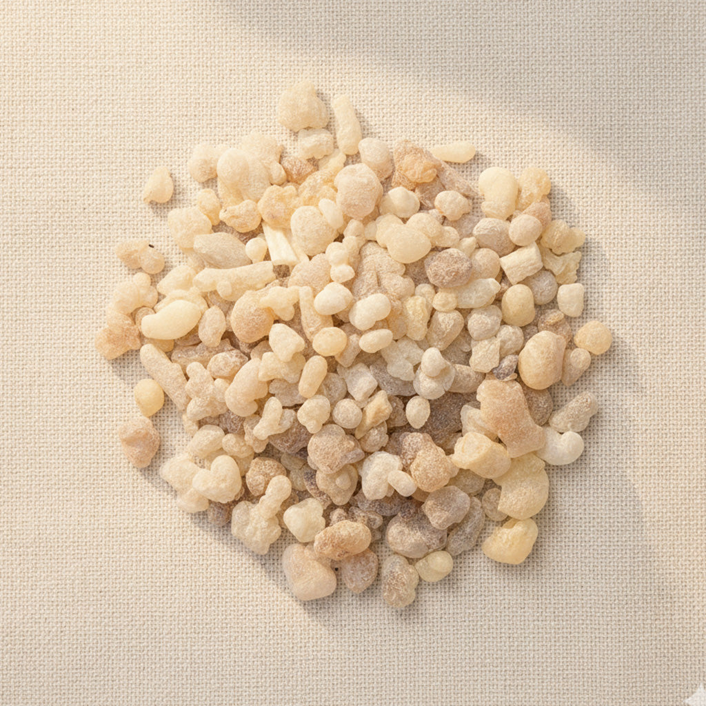 Top view of Boswellia sacra frankincense small tears on a neutral linen background, showing natural pale golden resin grains.
