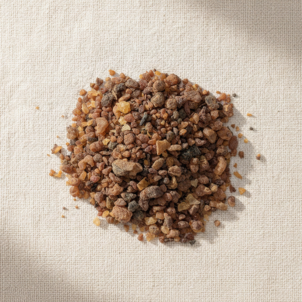 Natural myrrh resin pieces from Somalia, shown from above on a beige linen background, highlighting their warm amber tones and textured grains.