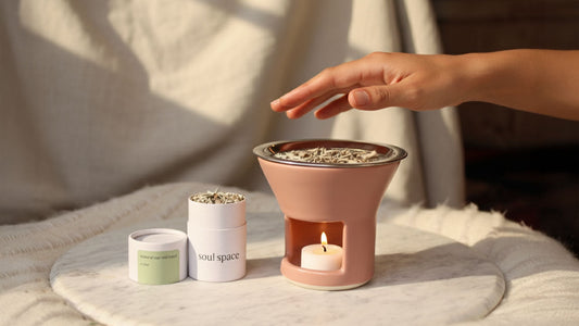 A hand hovers above a Soul Space incense warmer as a tealight gently heats botanical incense, releasing natural aroma in soft sunlight.