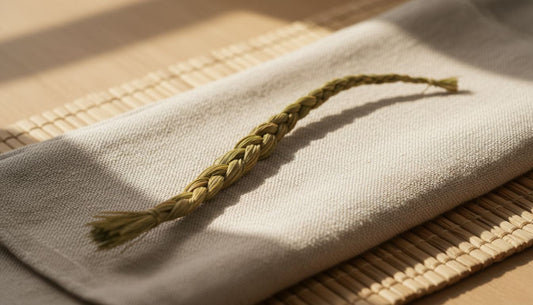 A single braid of sweetgrass resting on a folded linen cloth in warm natural light, symbolizing calm, mindfulness, and connection to nature.