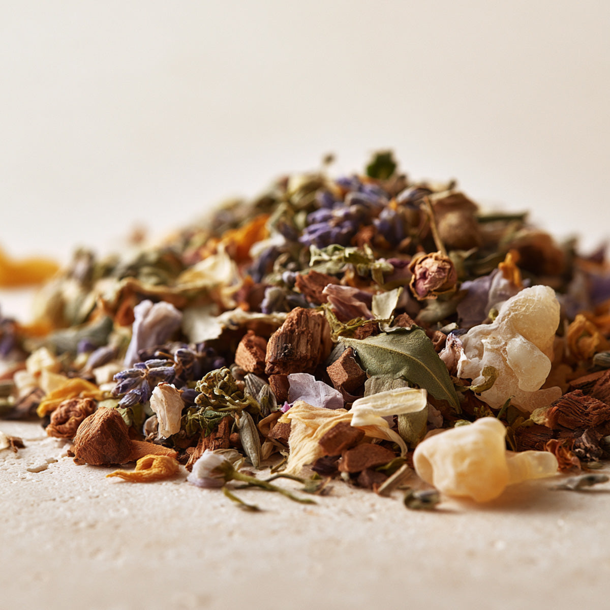 Close-up of loose botanical incense with resin, wood, herbs, and dried flowers