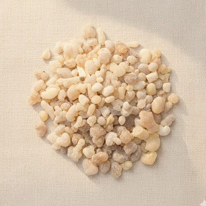 Top view of Boswellia sacra frankincense small tears on a neutral linen background, showing natural pale golden resin grains.