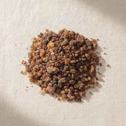 Natural myrrh resin pieces from Somalia, shown from above on a beige linen background, highlighting their warm amber tones and textured grains.